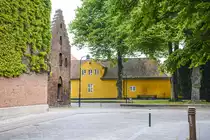 Das Backsteingeb�ude auf der linken Seite ist Teil des Dom zu Roskilde. Das gelbe Geb�ude auf der rechten Seite ist Teil des Museums f�r zeitgen�ssische Kunst (d�nisch Museet for Samtidskunst) in Roskilde.Aufnahme: 20. Juni 2023.