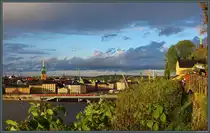 Der Monteliusv�gen entlang des Mariaberget im Stadtteil S�dra bietet einen guten Blick �ber die Innenstadt von Stockholm. Nach einem Regenschauer taucht die Sonne die H�user der Altstadt in leuchtendes Abendlicht. Heraus sticht der Turm der Deutschen Kirche St. Gertrud (Tystka kyrkan). (Stockholm, 17.05.2023)
