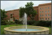 Vor der ehemaligen Gro�gastst�tte  Aktivist  sprudelt am 05.08.2023 der Springbrunnen. Im Hintergrund die denkmalgesch�tzten Geb�ude des Wohnkomlexes II im Stil des sozialistischen Klassizismus, die mit der 2. Baustufe der Planstadt Eisenh�ttenstadt 1953/54 errichtet wurden.