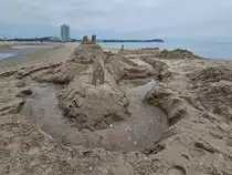 Blick auf eine Sandburg auf dem Priwall, im Hintergrund die markante Strandpromenade von Travem�nde. (April 2024)