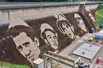 Dieses vergngliche Kunstwerk, geschaffen von Klaus Dauven im Jahr 2023, auf der Staumauer in Vianden.
Die Gesichter stellen Arbeiter dar, die am Bau der Staumauer in den 1950 – 1960er Jahren beteiligt waren. 
Das Kunstwerk wird in ca 5 - 6 Jahren nicht mehr zu sehen sein. 05.2024
