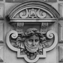 Diese verschleierte Dame befindet sich an der Fassade der Alten Post, einem ehemaligen Postgeb�ude und heutigem Hotel aus dem 19. Jahrhundert. (Flensburg, Juni 2024)