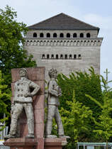 Das Drei-Mnner-Eck-Denkmal befindet sich auf dem Vorplatz des Haupbahnhofes in Wanne-Eickel. Im Hintergrund ist der Hochbunker zu sehen. (Juni 2024)