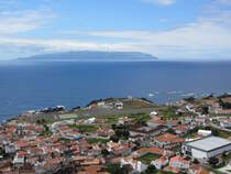 Der Ort Vila do Corvo, mit Flughafen, auf der Azoren-Insel Corvo am 20.07.2024. Hinten die Nachbarinsel Flores.