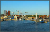 An der Mndung des Dange in das Memelhaff entsteht ein neues Stadtviertel unweit der Altstadt von Klaipėda. Im Vordergrund rechts neben dem Riesenrad startet die Personenfhre zur Kurischen Nehrung. Links sind hingegen noch alte Hafenanlagen zu sehen. (Klaipėda, 24.08.2024)