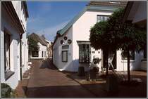 Der Ortskern von Greetsiel ist durch schmale Gassen gekennzeichnet. Hier ist der Fahrzeugverkehr weitestgehend verbannt. Scan eines Dias aus dem Sommer 2004.