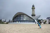 Der �Teepott� und der Leuchtturm vom Warnem�nder Strand aus gesehen. Der dreigeschossige Rundbau wurde 1968 errichtet.
Aufnahme: 8. Juni 2025.