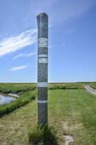Sturmflutmarkierungspfahl auf der Hallig Oland im Nordfriesischen Wattenmeer. Aufnahme: 1. Juli 2025.