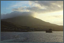 Morgenstimmung in Castlebay: Whrend sich der Berg Heaval in Wolken hllt, beleuchten die ersten Sonnenstrahlen den Ort. Im Vordergrund ist Kisimul Castle zu sehen. (Barra, 11.05.2025)