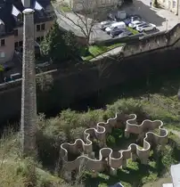 Der Schornstein F�ngerl�k im Pfaffenthal ist der einzige �berrest des Wasserwerkes das bis 1940 von hier mit einer Pumpstation angetrieben von einer Dampfmaschine das Wasser zum h�hergelegenen Limpertsberg hochpumpte. Die Skulptur neben dem Schornstein ist von der LUGA von letzten Jahr. Das Luga-Solum ist ein Schilfrohrgeflecht auf luxemburgischen Sandstein. Aufgenommen von der Roten Br�cke (Pont Grand duschesse Charlotte) in der Stadt Luxemburg 01.04.2026