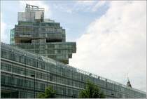 Zwei Trme in Hannover: im Vordergrund das Hochhaus der Nord LB und rechts ist noch die Spitze des Rathausturmes zu erkennen.
Obwohl vllig verschieden in ihrer Architektur, gibt es doch auch hnlichkeiten. Beide Trme sind von zu den jeweiligen Bauwerken gehrenden flacheren Bauteilen umgeben und beide prgen das Stadtbild. Das Bankgebude wurde von den Stuttgarter Architekten Behnisch, Behnisch und Partner entworfen. 17.08.2006 (Matthias)