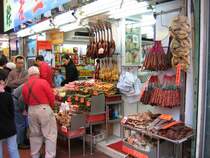 Hong Kong - Szenen auf einem Strassenmarkt zwischen Hopewell Center und Hennessy Rd. Ein Potpourri exotischer Dfte und Speisen... platte Enten, platte Hhner, Wrste, Trockenfisch, getrocknete Enten und Hhner. Das gibt sicher ein leckeres Essen fr den herren im roten Pullover und fr sie Familie im Hintergrund.