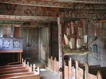 Blick in die Stabkirche von Kvernes. Die Rosenmalereien ist ein typischer Bestandteil der Stabkirchen. Das an der Decke h�ngende Schiff ist ein typisches Merkmal f�r die K�stenregion. Es soll Segen und Schutz f�r die Fischer und Seefahrer bringen. 