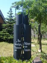  Den ehemaligen Bewohnern von Pillkoppen zum Gedenken 
Dieses Denkmal steht in einem Vorgarten in Pillkoppen.
Pillkoppen ist ein kleines Dorf auf der Kurischen Nehrung. (russischer Teil). Das Denkmal stellt das Segel eines Schiffes dar, Pillkoppen war einst ein ostpreu�isches Fischerdorf.