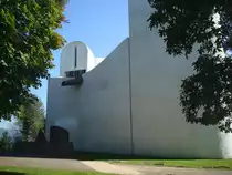 Wallfahrtskirche in Ronchamp / Frankreich, 
die fensterlose Westseite mit skulpturartigem Wasserspeier, dahinter der Nordturm und einer Brunnenskulptur vor der Wand,
Sept.2010