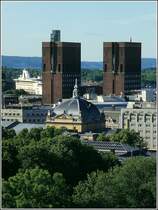 Blick ber die Dcher von Oslo. Hinter der Kuppel des Nationaltheaters erheben sich die Trme des Osloer Rathauses. Dahinter schiebt sich ein Fhrschiff durch den Hafen. Scan eines Dias aus dem Juni 1994.