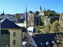Luxemburg,vorne im Bild an der Alzette: die Abtei Neum�nster und die Johanneskirche, auch St. Johann auf dem Stein genannt. Oben links: die T�rme der Kathedrale (urspr�nglich eine Jesuitenkirche, deren Grundstein 1613 gelegt wurde). Ende des 18. Jahrhunderts nahm die Kirche das Gnadenbild der Tr�sterin der Betr�bten, der Stadt- und Landespatronin, auf. Oben rechts: die St.-Michaelskirche ist das �lteste erhaltene sakrale Bauwerk der Stadt. Im Jahre 987 stand an der Stelle der heutigen St.-Michaelskirche die Burgkapelle der Luxemburger Grafen. Von links nach rechts auf dem Felsen, der Corniche Spazierweg, auch “der sch�nste Balkon Europas” genannt, verl�uft auf den von Spaniern und Franzosen im 17. Jahrhundert errichteten W�llen entlang des Alzette-Tales. Von der Rue de la Tour Jacob aus gesehen am 15.10.2011 
