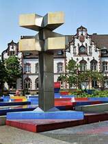 Brunnen auf dem Viktoriaplatz. Das neugotische Gebude im Hintergrund war einmal die Hauptpost, heute ist es das stdtische Kunstmuseum (25. Mai 1989). Der Brunnen wurde von dem Knstler Otto Herbert Hajek gestaltet. Die Meinungen darber sind geteilt. Es ist jedoch zu bercksichtigen, dass sich die Konzeption des Knstlers wohl nur bei der Draufsicht vllig erschliet, die aber allenfalls aus den umgebenden Husern mglich ist.