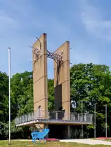 . Saarland - Das Europadenkmal in Berus in der Gemeinde berherrn. 18.07.2014 (Jeanny)

Das Europadenkmal besteht aus zwei senkrecht aufragenden, 16 m hohen Betonplatten, die in ihrem unteren Teil eine Aussichtsplattform mit durchsichtigem Gelnder durchbrechen. An ihren oberen Enden sind die beiden rechteckigen Pylone mittels eines Strahlenbndels aus mehreren Metallstben miteinander verbunden. Auf der Innenseite der beiden Pylone ist oberhalb der Plattform in Augenhhe eine Gedenktafel fr die Politiker Konrad Adenauer, Robert Schuman und Alcide De Gasperi angebracht. Weitere Plaketten fr Helmut Bulle, Josef Besch und Paul Henri Spaak wurden nach der Einweihung angebracht.

Das Europadenkmal ist heute das Wahrzeichen der Grenzgemeinde berherrn. Seine Lage und die Aussicht machen das Denkmal zum beliebten Haltepunkt auf Spaziergngen und Ausflgen. Die Stirnseite des Denkmals ist ungefhr in Richtung auf Saarbrcken orientiert, was auf die uralte Brckenfunktion des Saarraumes als Kreuzungspunkt von Fernwegen und auf seine weit jngere Brckenfunktion im deutsch-franzsischen Verhltnis verweist. Gerald Motsch versuchte, die deutsch-franzsische Geschichte im Laufe der Jahrhunderte in vertikaler Form durch die beiden Platten ins Bild zu setzen. Die horizontale Plattform des Denkmals signalisiert die gemeinsame historische Wurzel der beiden Nationalstaaten im keltisch, romanisch und germanisch geprgten frhgeschichtlichen Kulturraum. Whrend die Betonplatten auer im Untergrund und in der Plattform nirgends verbunden sind, wurde in ihrem oberen Teil durch die gebndelten Stbe eine Verbindung aus Metall, d.h. aus einem anderen Material geschaffen.

Der blaue Hirsch im Vordergrund erinnert an das Jahr 2007, als Luxemburg gemeinsam mit der Groregion europische Kulturhauptstadt war. Er diente als Logo dieses Ereignisses. 