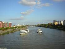 Frankfurt am Main, Wohnen am Fluss: Blick von der Flerbrcke auf den Main in Richtung Osten, im Bildhintergrund die Deutschherrnbrcke, eine Bahn- und Fussgngerbrcke. Die Huser an den Bildrndern entstanden erst in den letzten Jahren. Im Bild links das Gelnde der ehemaligen Weseler Werft, ein ehemaliger Umschlagplatz fr mit dem Binnenschiff angelieferte Baustoffe. Die Weseler Werft wurde zwischen 2000 und 2005 zu einer Grnanlage umgestaltet. Einige ehemalige Hafenkrne wurden als technische Baudenkmler erhalten. Sie sind heute Teil der Route der Industriekultur Rhein-Main.


