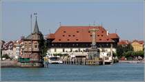 Konstanz. Bei der Anreise mit dem Schiff sieht man hinter der Hafeneinfahrt, die vom ehemaligen Leuchtturm und der Imperia begrenzt wird, das Konzil. 10.07.2015