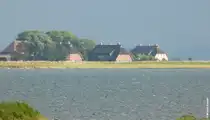 Von der kleinen Insel Ummanz geht der Blick auf die gro�e Nachbarinsel R�gen: Kurz zuvor ging ein Regenschauer hinunter, aber jetzt scheint kurz die Sonne auf diese Reetdach gedeckte H�user (September 2012)