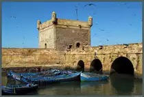 Die Scala du Port ist eine alte Festungsanlage aus der portugiesischen Besatzungszeit, welche den Hafen von Essaouira sch�tzte. Heute wird die Anlage als Museum und Aussichtspunkt genutzt. Vor dem Turm liegen einige der typischen blauen Fischerboote vor Anker. (Essaouira, 21.11.2015)