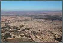 Aus dem startenden Flugzeug bietet sich am 25.11.2015 noch einmal ein letzter, beeindruckender Blick auf die Stadt Marrakesch: In der Mitte ist die dicht bebaute Medina zu sehen, welche von einer Stadtmauer umgeben ist. Im Zentrum befinden sich der Djam�a el-Fna sowie die Kutubiya-Moschee (links davon). Am unteren Bildrand ist in der Mitte die Kasbah-Moschee zu erkennen, wo sich auch die Saadiergr�ber befinden. Rechts davon ist der El-Badi-Palast zu sehen. Links, au�erhalb der Medina, schlie�t sich die Neustadt an.