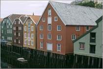 Trondheim. Die auf Pfhlen stehenden Lagerhuser am Nidelva zeigen die typische, dreifarbige Farbgebung: weie Fensterrahmen, farbige Fensterumrandungen und Fassadenflchen in einer weiteren Farbe. Scan eines Dias vom Juni 1994.