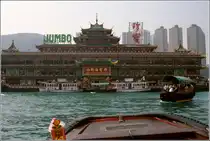 Das  Jumbo  in Aberdeen an der S�dk�ste von Hong Kong Island ist ein riesiges, mehrst�ckiges, schwimmendes Restaurant. Aberdeen kann man gut bei einer Fahrt mit einem Walla-Walla, das sind kleine Boote wie das rechts im Bild, kennenlernen. Scan eines Dias vom Januar 1997.