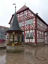 Stadtlauringen, altes Rathaus am Marktplatz, zweigeschossiger Fachwerkbau mit einseitig abgewalmten Satteldach und dreischiffiger Halle im Erdgeschoss, erbaut 1563 (25.03.2016)