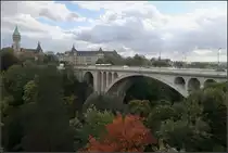 . Pont Adolphe in Luxemburg -

Die Adolphe Br�cke f�hrt �ber das Tal der P�trusse hinweg und ist einer von drei gro�en Stra�enviadukte, die die Innenstadt von Luxemburg �ber die umgebenden T�ler hinweg mit den angrenzenden Stadtteilen verbinden. Zwei dieser Br�cken werden zuk�nftig auch von der Luxtram befahren werden. Von 2014 bis 2017 wurde die Pont Adolphe saniert und dabei auch Gleise f�r die Stra�enbahn verlegt. Ersetzt man auf der Aufnahme gedanklich den Bus durch eine Tram, hat man das sp�tere Bild vor Augen, da die Stra�enbahn wie auch auf der Pont Grande-Duchesse Charlotte hier im Akkubetrieb ohne Oberleitungen betrieben werden.

Im Rahmen der Sanierung wurde unter die Stra�enfahrbahn der Pont Adolphe ein Steg zwischen die beiden Br�ckenh�lften eingeh�ngt, der vor allem f�r Radfahrer aber auch f�r Fu�g�nger gedacht ist. Aus dieser Perspektive ist dieser Steg kaum wahrnehmbar.

03.10.2017 (M)