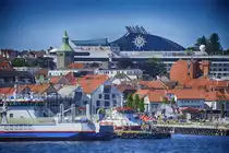 Die Innenstadt von Stavanger von der Tau-Stavanger-F�hre aus gesehen. Im Hintergrund ist ein riesiges Kreuzfahrtschiff zu sehen. Aufnahme: 3. Juli 2018.
