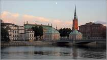 Stockholm. Blick von der Strmgatan hinber nach Gamla Stan und Riddarholmen. Von links sind im Bild folgende Gebude zu sehen: das weie Gebude ist der Hgsta Domstolen (Oberster Gerichtshof), das grne Dach rechts daneben gehrt dem Riddarhuset. Der markante Kirchturm der Riddarholmskyrkan berragt die Szenerie, rechts daneben ist das Gamla Riksarkivet zu sehen. 22.07.2018