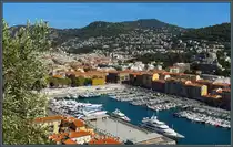 Im Hafen von Nizza liegen zahlreiche Yachten vor Anker. Dahinter beginnt der Stadtteil Riquier. Auf den Bergen im Hintergrund sind links das Observatorium und rechts der Funkturm zu erkennen. (Nizza, 26.09.2018)