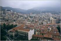 Monaco. Blick vom Stadtteil Monaco-Ville auf den unterhalb gelegenen Stadtteil La Condamine und die dahinterliegenden Stadtteile, die sich den Berghang hinaufziehen. Scan eines Dias vom Sommer 1979.