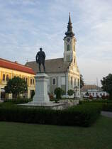 Baja, St. Peter und Paul Kirche am Toth Kalman Ter, erbaut bis 1765, davor das Denkmal fr den Dichter Kalman Toth (24.08.2019)