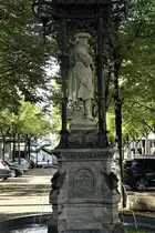 Hamburg am 1.10.2020: denkmalgesch�tzter „Vierl�nderin-Brunnen „ steht seit 1975 auf historischen Hopfenmarkt.
Er erinnert an die Vierlande als die Hauptlieferanten f�r Hamburgs M�rkte.
Der Brunnen entstand 1878 nach Pl�nen von Friedrich Johann Lorenz Meyer, die Statue wurde von Engelbert Peiffer gefertigt. 
Der steinerne, im Brunnenbecken stehende, Statuensockel tr�gt um seine vier Seiten herum verteilt die Inschrift: „Auf dem Markt lernt man die Leute kennen“. Auf dem Sockel sitzen vier wasserspeiende Enten, die aus Bronze gefertigt sind. 2019 wurde die Restaurierung abgeschlossen.
