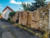 Historischer Steinzaun mit eingebautem Rastbank. Ausser der Innenstadt findet man im Stadteil Tettye noch ziemlich viel Altbau. Foto: 07.2020, Ungarn, Pcs, Kisboldogasszony utca.