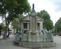 Hamburg am 1.8.2021: Der Mnckebrunnen und das dahinter liegende Gebude wurden vom damaligen Oberbaudirektor Fritz Schumacher entworfen und 1926 fertiggestellt. Die Bronzen stammen aus der Werkstatt des Knstlers Georg Wrba. Das Gebude mit den Sulen war eine ffentliche Bcherhalle und wurde 2009 in ein Kulturcaf umgewandelt. Das Ensemble entstand zum Gedenken an den Hamburger Brgermeister Johann Georg Mnckeberg (1839-1908)