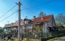 Dieses Foto habe ich in Pcs, in der Stadtteil  Erzsbettelep  (Elisabethsiedlung) gemacht. Dieser Stadteil wurde durch die Donaudampfschiffgesellschaft gegrndet. Die  Kolonie  stand aus 4 Strassen und 32 Huser. Es gab 6 kleine Wohnungen pro Haus zzgl Gartenteil und Nebengebude. Vor ca. 100-120 Jahren wurden neue Kohlenminien in der Nhe erffnet und die dort arbeitenden haben hier Wohnungen bekommen. Die Siedlung hie ursprnglich Ullmannsiedlung, genannt nach einem Leiter des Unternehmens. 1938 wurde auf Elisabethsiedlung umbenannt (von Elisabeth Amalie Eugenie von Wittelsbach Knigin genannt). Die Huser waren berdurchschnittlich ausgerstet, da Leitungswasser und Strom auch vorhanden war. In den vergangenen guten Jahrhundert wurde es nicht geregelt wie man die Gebuden/Wohnungen ndern, erweitern, umbauen oder zusammenlegen/vereinigen darf. Deswegen ist auf heutzutage das Strassenbild ganz ganz gemischt (und daher meiner Meinung nach, sehr einzigartig und interessant) geworden. Die Etagen wurden gendert, Dachgeschosse wurden eingebaut...daher findet man hier keine zwei gleiche Huser. Die groe nderungen sind um ca 1926 begonnen. Wegen der damaligen Wohnungsmangel hat die Stadt 2/3-tel der Siedlung in Miete genommen und hat unter anderem eine Kirche und Schule erbaut und geffnet. Aufnahmezeit: November 2020. 
Auf diesem Bild lohnt es sich die Dcher anzuschauen. 1Deckung = 1Besitzer = 1 Wohnung