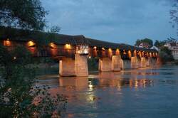 Holzbrücke - Die Lichter der 400 Jahre alten Brücke, nach Plänen des bekannten Brückenbaumeisters Blasius Baldischwiler, spiegeln sich im ruhigen Wasser des Rheins.
