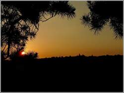 Am Abend liegt die Ortschaft Noertrange im Gegenlicht des Sonnenuntergangs, wenn man in Wiltz auf der Anhhe 