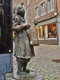 Das Printenmädchen, eine Bronzefigur mit einer großen Printe in den Händen, steht in Aachen an der Ecke Körbergasse-Büchel vor dem ältesten Aachener Cafe.